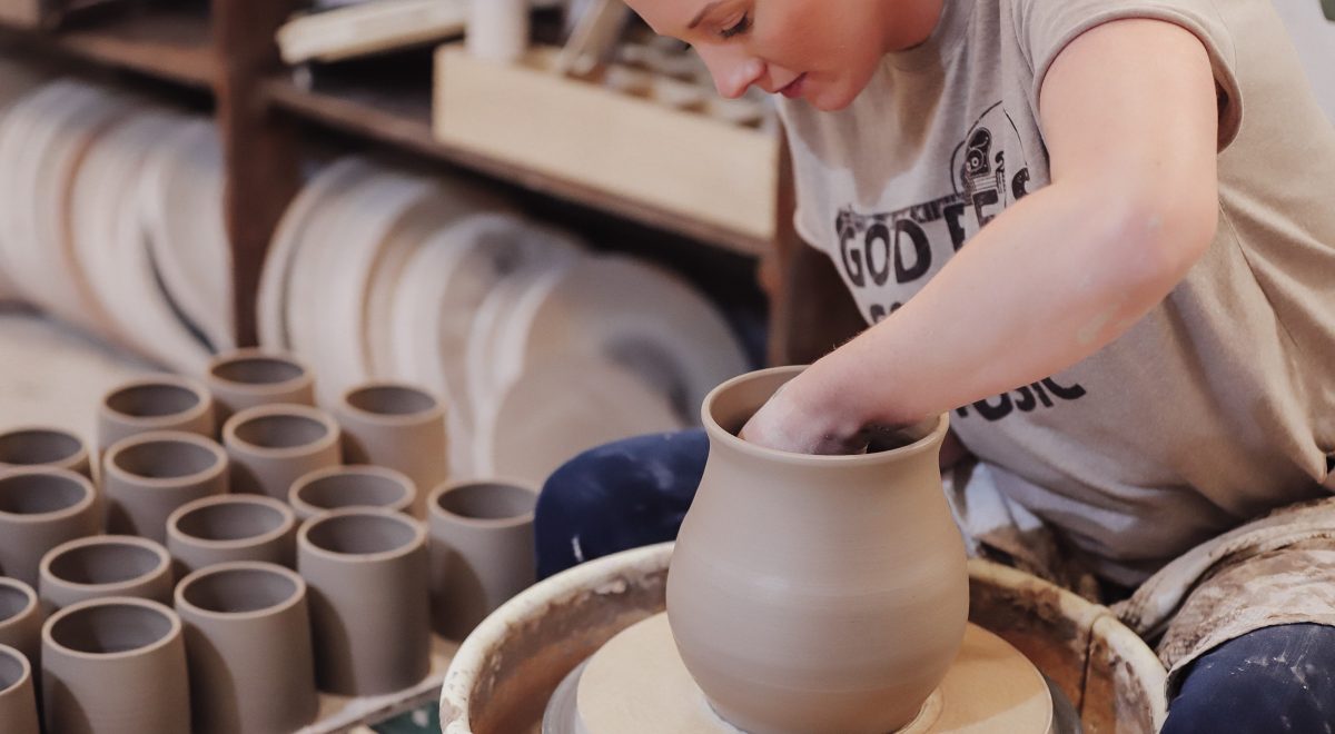 Image of Rachel Sherrill of Studio RK in motion at turntable, creating a ceramic pot.