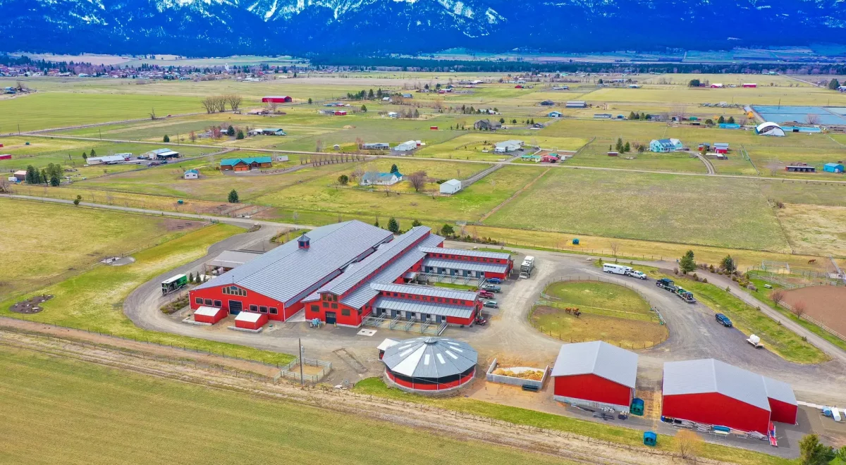 Aerial perspective of Hot Property equine facility barn, displaying spacious stable areas, open fields, outdoor arenas, and large storage barns.