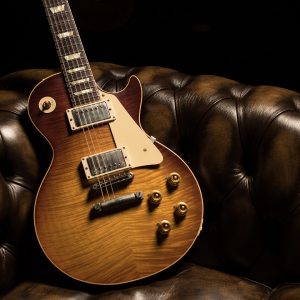 Gibson Les Paul 1959 Burst guitar leaning in a leather chair.