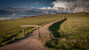 The front gate of the Kokopelli Ranch property, which opens to a winding road across a Montana meadow.