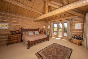 The master bedroom of the Kokopelli Ranch main house is a spacious and cozy room with rustic finishes and a personal balcony.