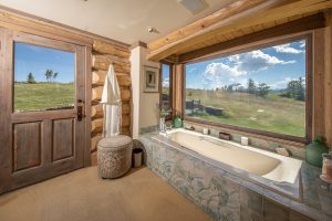 The master bathroom of the Kokopelli Ranch main house features a large luxury bathtub and large windows overlooking the Montana mountains.