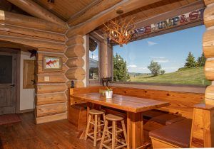 A secondary dining area of the Kokopelli Ranch house, which features booth-style seating and a large window overlooking the Montana mountains.