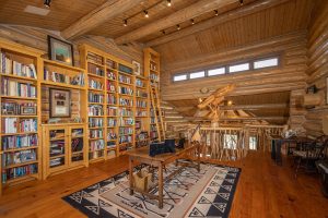 The upstairs study and office space of the Kokopelli Ranch house, featuring floor-to-ceiling bookcases covering the walls with books.