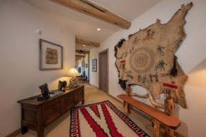 The main hallway of the Kokopelli Ranch features Western influences, including a vintage buckskin art piece and other Indigenous art.