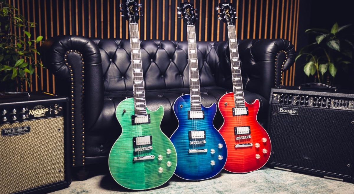 The Gibson LP Modern Figured guitar in green, blue, and red, leaning against a black leather couch in a recording studio.