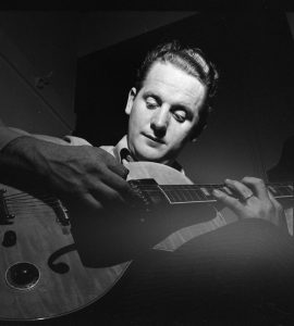 Les Paul playing a Gibson guitar against a black background circa January 1947.