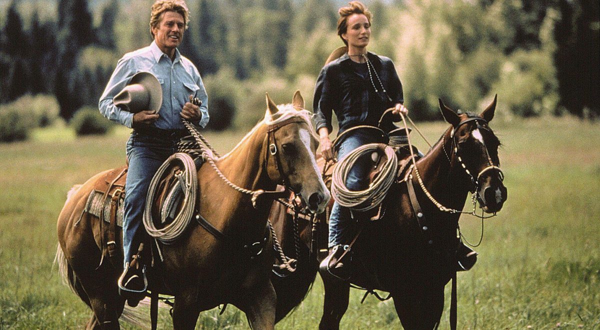 Actors Robert Redford and Kristen Scott Thomas ride horses across a pasture in the 1998 film "The Horse Whisperer."