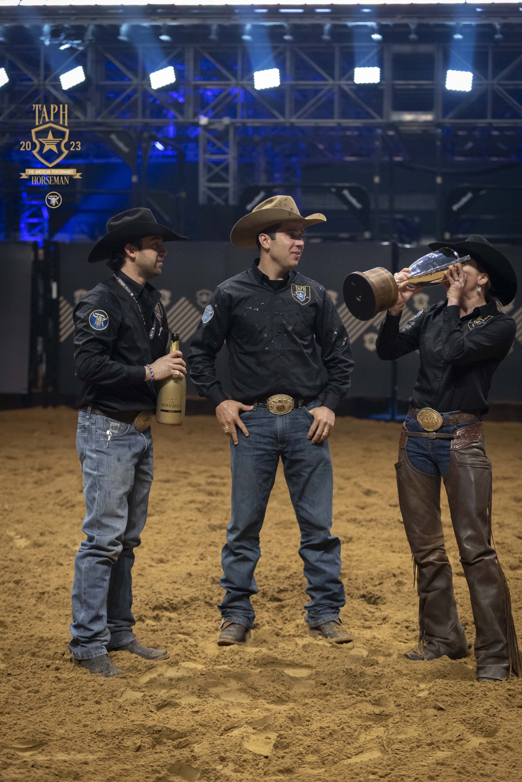 Sarah Dawson (right) drinks champaign from the American Performance Horseman trophy as Fernando Salgado (middle) and Adan Banuelos (left) look on.