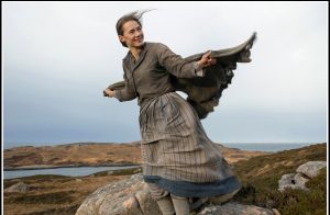 Actress Caren Pistorius holds her shawl in the wind with the ocean in the background in the 2015 film "Slow West."