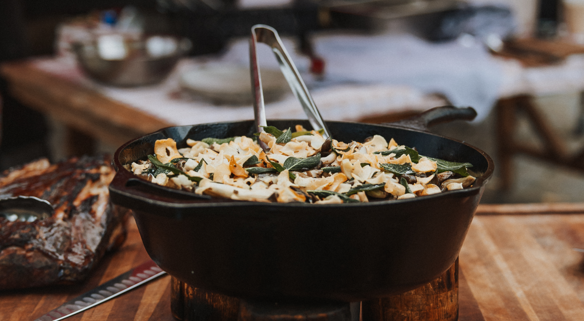 A cast-iron skillet full of pig roast sitting on a wooden table.