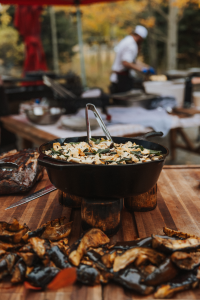 A cast-iron skillet full of pig roast sitting on a wooden table.