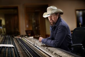 Toby Keith sitting in a recording studio.