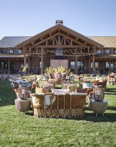 Luxury outdoor seating arranged in front of the Brush Creek Ranch lodge, with fur-covered cushioned couches, chairs, and tables.