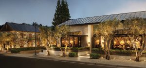 The exterior of RH Restaurant in Yountville — a well-lit chic stone structure lined with trees.