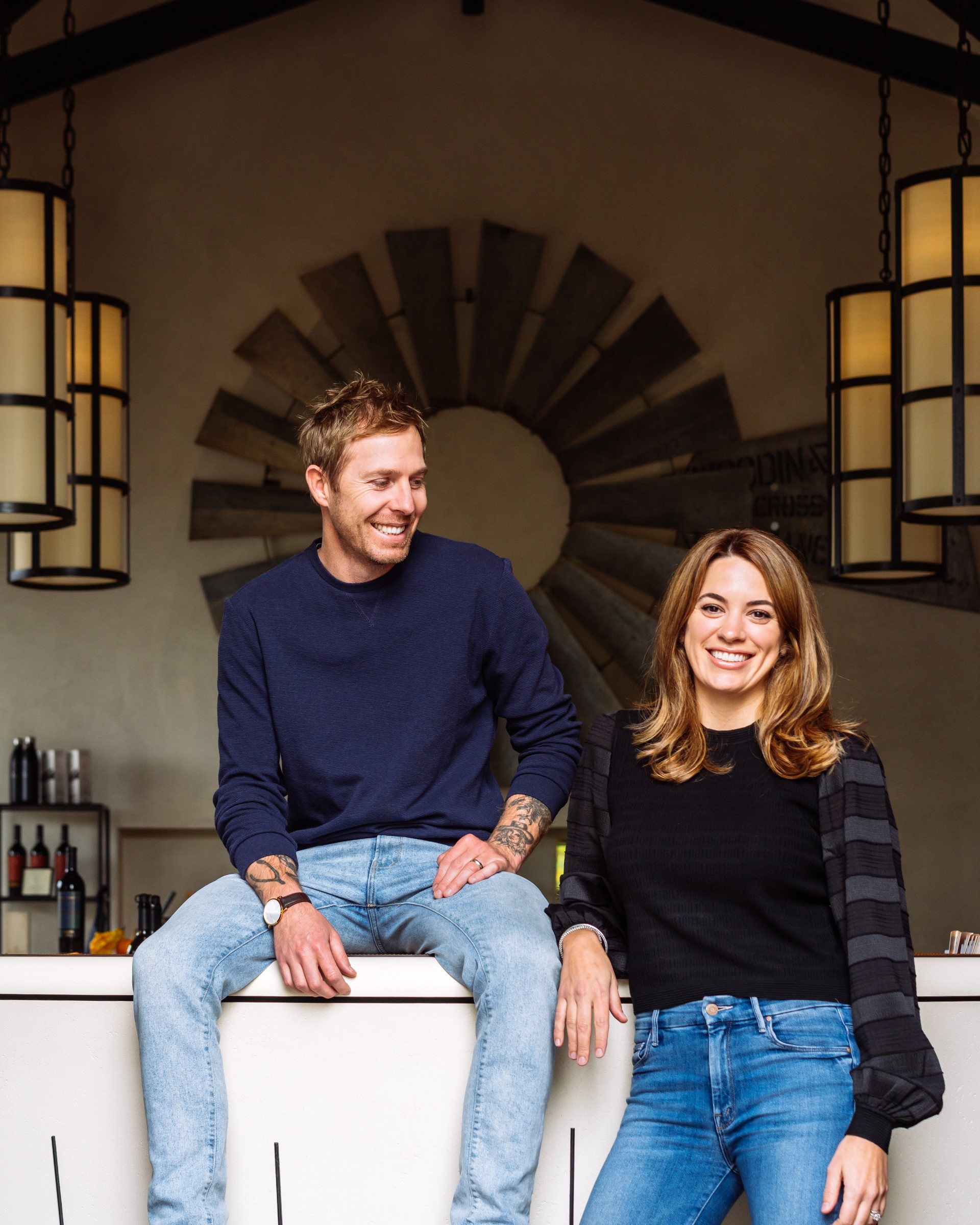 Winemaker Blair Guthrie and CEO of Steward Cellars Caroline Stewart Guthrie lean against a bar and smile at the camera.