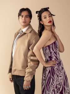 Kiowa Gordon (left) and Jessica Matten (left) pose in garments by Lesley Hampton against a tan backdrop at the 2024 SWAIA Native Fashion Week.