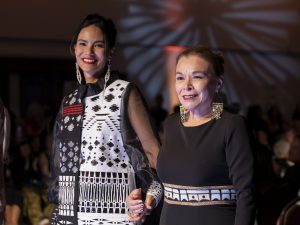 Jessica Matten walks down the runway hand-in-hand with Himikalas Pamela Baker during the 2024 SWAIA Native Fashion Week.
