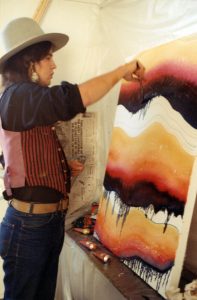 Earl Biss paints an orange, red, and black background on a white canvas in San Francisco, 1969.