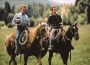 Actors Robert Redford and Kristen Scott Thomas ride horses across a pasture in the 1998 film "The Horse Whisperer."