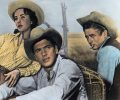 Actors Elizabeth Taylor (left), Rock Hudson (middle), and James Dean (right) pose in classic cowboy and cowgirl outfits in the 1956 film "Giant."