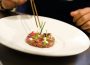A chef uses cooking pliers to delicately place garnish onto a wagyu tartare at the Brush Creek Ranch restaurant.